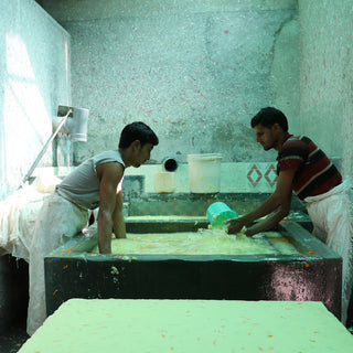 two men with their hands making the garment pulp into paper sheets