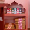 Shop display of Molly Mahon eco paints on shelving with detailed carving of an Indian temple roof 