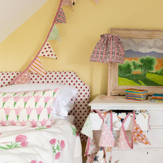 An attic room with twin single beds upholstered headboards, cushions, eiderdowns and lampshades to match in molly mahon's hand block printed greencombe collection bringing uplifting colour and joy to the space