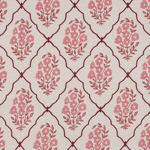 A close-up of a fabric or wallpaper pattern featuring a repeating trellis design in dark red on a warm cream background, with pink floral motifs inside each diamond.