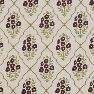 A close-up of a fabric pattern featuring dark brown floral clusters and olive green leaves, framed by a gold trellis design on a warm beige background.