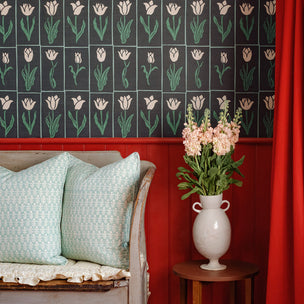Decorative room with black and green luxury floral wallpaper, red paneling, and vase with flowers on a table.