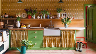 Colorful kitchen with green cabinets, yellow walls, and decorative elements.