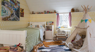 Molly Mahon fern wallpaper in a child's bedroom with tipi tent, toys and soft cuddly teddy bears in a Sussex eves room with a small narrow window