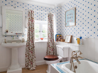 bathroom wallpapered in molly mahon's spot and star design with a white wood panel to protect from the water