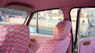 Ambassador Indian taxi upholstered in Molly Mahon hand block printed Bagru pink design finished off with Molly Mahon hand block printed Mughal design window curtains tied back giving an injection of colour and joy for the passenger